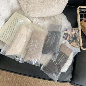Detail of four pairs of thick winter socks in neutral colors with zipper bag packaging