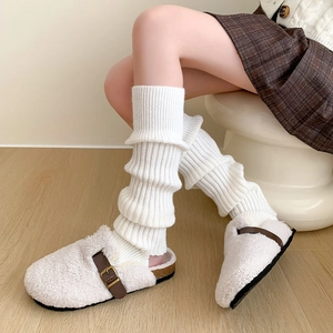 Détail de jambières en maille blanche portées avec des chaussons en sherpa et liège