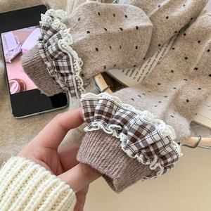 Detail of wool socks with black polka dots, lace trim, and brown checkered ruffle edges