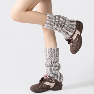 Détail du tricot des jambières gris-blanc portées sur des baskets pour un look d'hiver