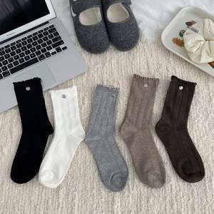 Close-up of five pairs of frill cuff socks in neutral tones with metal button detail