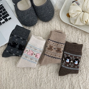Flat lay of four thick winter knit socks with cute animal patterns in autumn colors