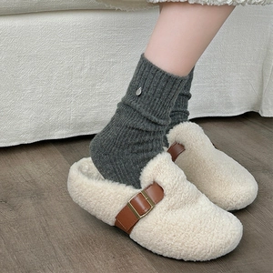 Plush beige faux fur mule slippers with brown leather buckle strap and gray knit socks