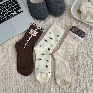 Three pairs of floral and striped mid-calf knit socks in brown, cream, and beige colors