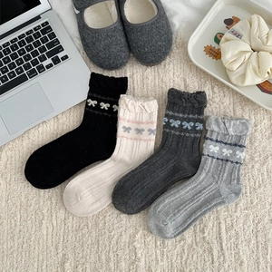Detail of wool socks with ribbon bows and wavy edges in four neutral colors