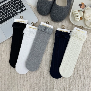 Close-up of five pairs of lace-trimmed cable knit socks in black, white, and neutral tones