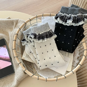 Close-up of vintage wool socks with polka dots, lace trim, and plaid ruffles in a basket