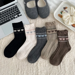 Detail view of wool socks with bubble lace trim and bow patterns in five vintage colors