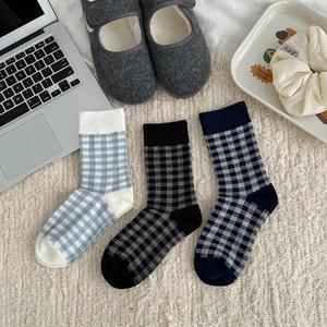 Detailed view of three pairs of gingham checkered cotton crew socks on a cozy rug