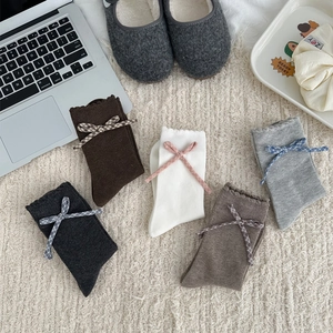 Détail de cinq paires de chaussettes avec nœuds à carreaux et bords festonnés sur tapis