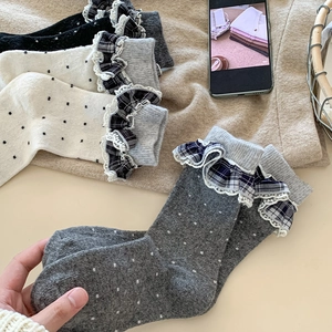 Close-up of vintage wool socks with white polka dots and plaid lace trim edges