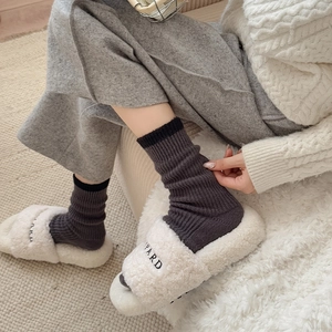 Detail of thick grey thermal knit socks paired with plush cream fleece slippers