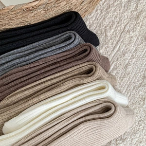 Close-up of assorted ribbed knit slouch socks in neutral colors on soft background