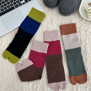 Flat lay of four pairs of colorful Japanese style two-toe socks on a cozy rug
