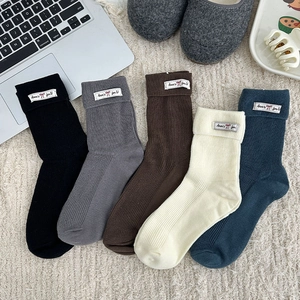 Detailed close-up of five-color ribbed knit crew socks with folded cuffs and woven labels