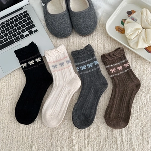 Detail of wool socks with frilly cuffs and bow patterns in four warm autumn colors