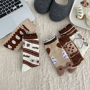 Détail de chaussettes en coton marron avec oursons et motifs de cœur sur tapis