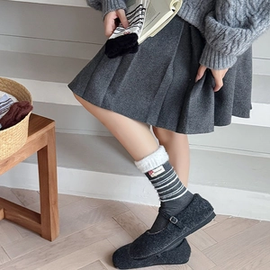 Detail von gestreiften Wollsocken mit Plüschbündchen und grauen Mary Jane Filzschuhen