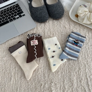 Close-up of four pairs of sweet floral and striped crew socks on white faux fur rug