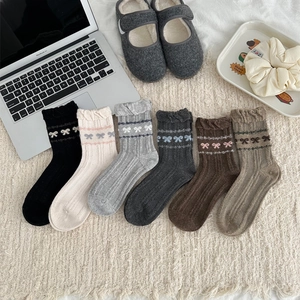 Macro detail of six pairs of wool blend socks with bow patterns and scalloped cuffs