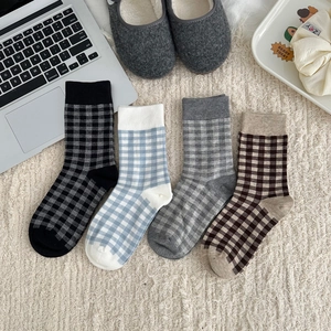 Detailed view of checkered crew socks in blue, black, gray and coffee on plush background