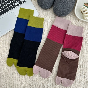 Japanese style color-block tabi socks with ribbed texture on a cozy home rug
