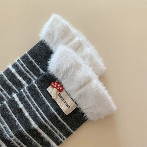 Makroaufnahme bunter Strickstrümpfe mit Webpelz-Besatz und Stickerei-Mushroom-Label