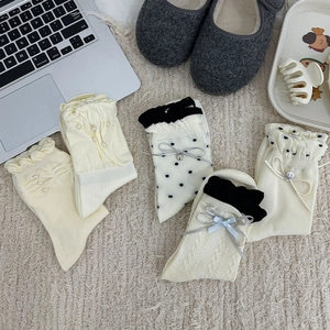 Collection de chaussettes blanches avec perles, nœuds et volants sur fond beige doux