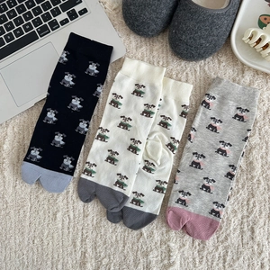 Chaussettes tabi à motifs de chiens colorés posées sur un tapis blanc moelleux