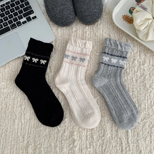 Detailed knit texture of wool blend socks with bow patterns and scalloped edges