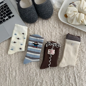 Detail of four floral and striped cotton crew socks with ruffles and cute embroidery