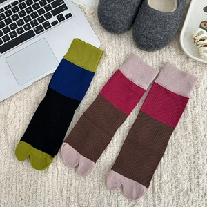 Close-up of color-block Tabi socks with ribbed knit texture in a cozy home setting