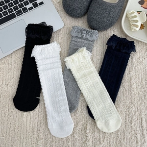 Close-up of cable knit cotton socks with delicate lace trim in five neutral colors