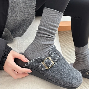 Detail of dark grey felt clog shoe with metal buckle and grey ribbed vertical stripe sock