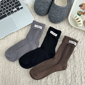 Three pairs of ribbed knit socks in grey black and brown with cute label details