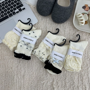 Détail de cinq chaussettes crème avec perles, dentelle et nœuds pour un style de vie douillet