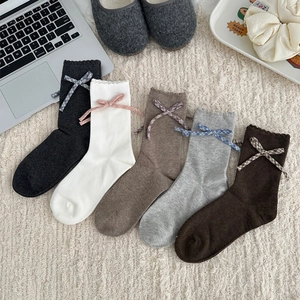 Cinq chaussettes mi-hautes avec nœuds à carreaux et bords à volants sur tapis