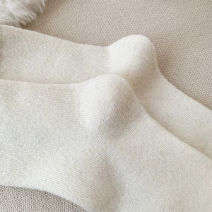 Detail of soft cream-colored wool knit socks showing high-quality heel weaving texture