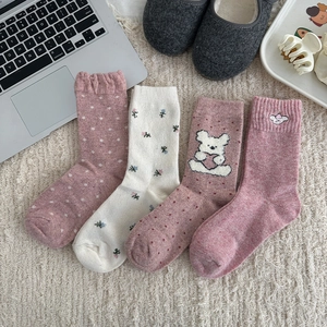 Four pairs of warm pink wool socks with floral patterns on a cozy plush background