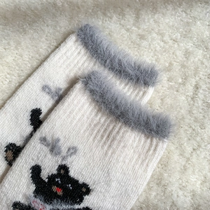Close-up of white wool socks with thick grey faux fur trim and cute bear pattern details