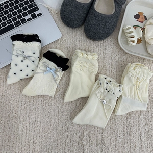 Détails de chaussettes à volants avec perles, pois et nœuds sur un tapis moelleux
