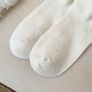 Close-up of seamless toe stitching on cream white knit cotton crew socks for women