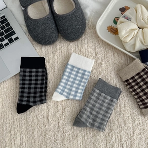 Flat lay of four pairs of checkered crew socks in blue, brown, grey and black colors