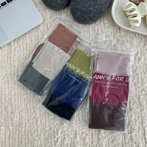 Three pairs of color-block split-toe socks in individual packaging on a soft white rug