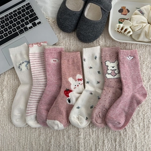 Flat lay of pink and beige floral knit socks set with cute embroidery on soft background