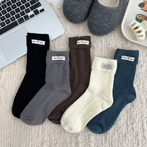 Five pairs of ribbed slouch socks for women in various colors with decorative labels