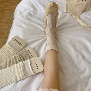 Détail du revers à volants et de la texture côtelée sur chaussettes montantes crème