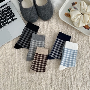 Flat lay of five pairs of plaid cotton socks in blue and brown on a cozy beige carpet