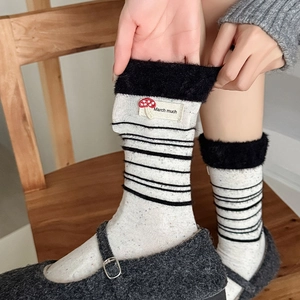 Detailaufnahme der Streifensocken mit Pelzbesatz und süßem Pilz-Aufnäher-Design