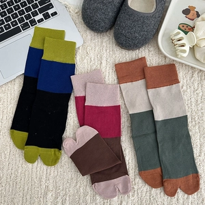 Detail of colorful split-toe socks in ribbed knit cotton on a cozy home background